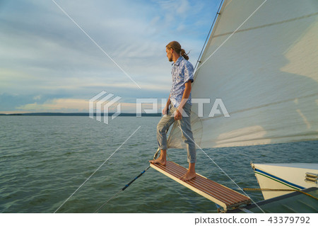 Young man standing on front of yacht and looking at sea 43379792