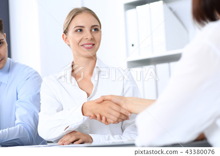 Business handshake by blonde woman and her partner at meeting. Concept of success and agreement Business handshake by blonde woman and her partner at meeting. Concept of success and agreement 43380076