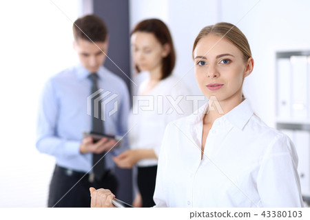 Beautiful blonde businesswoman standing straight in a brightly lit office at the background of Beautiful blonde businesswoman standing straight in a brightly lit office at the background of 43380103