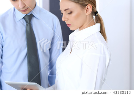 Beautiful blonde business woman using tablet or touch-pad with her male colleague or partner in Beautiful blonde business woman using tablet or touch-pad with her male colleague or partner in 43380113