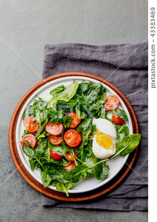Fresh summer salad with baby spinach, tomatoes cherry and egg. Top view, copy space. Slate gray 43383469
