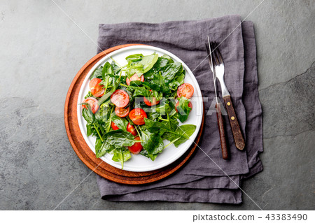 Fresh summer salad with baby spinach and tomatoes cherry. Top view, copy space. Slate gray Fresh summer salad with baby spinach and tomatoes cherry. Top view, copy space. Slate gray 43383490