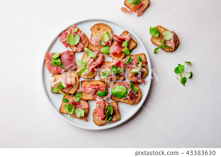 Mini open sandwiches with jamon serrano on white plate 43383630