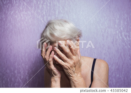 Portrait of an elderly woman with face closed by hands 43385042