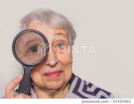 portrait of senior woman looking through a magnifying glass over white background portrait of senior woman looking through a magnifying glass over white background 43385062