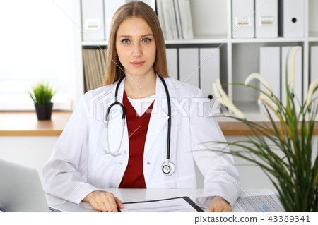Brunette female doctor using laptop computer in hospital. Healthcare, insurance and medicine concept Brunette female doctor using laptop computer in hospital. Healthcare, insurance and medicine concept 43389341