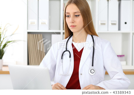 Brunette female doctor using laptop computer in hospital. Healthcare, insurance and medicine concept 43389343