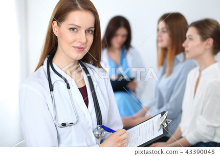 Young beautiful female doctor smiling while consulting her patient. Physician at work. Medicine and 43390048
