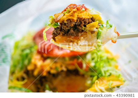 A dish of Okinawan specialty taco rice topped with cheese and salsa sauce. 43390981