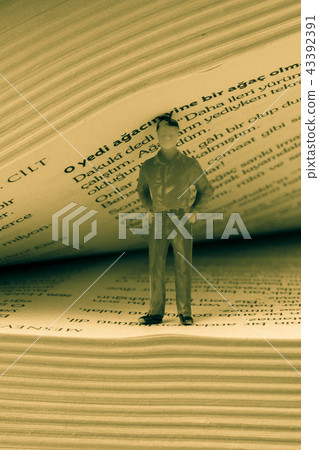 Figurine standing inside the pages of a book Figurine standing inside the pages of a book 43392391