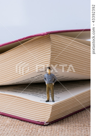 Figurine standing inside the pages of a book Figurine standing inside the pages of a book 43392392