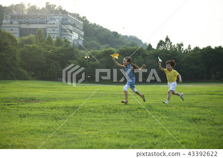 Two children blowing paper airplanes Two children blowing paper airplanes 43392622