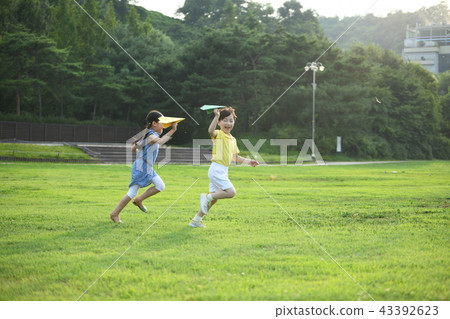Two children blowing paper airplanes Two children blowing paper airplanes 43392623