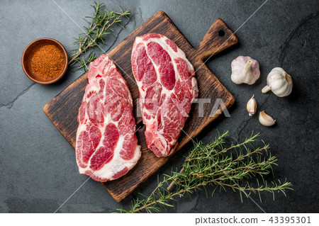 Raw pork steaks with seasoning on wooden board. Gray slate background Raw pork steaks with seasoning on wooden board. Gray slate background 43395301