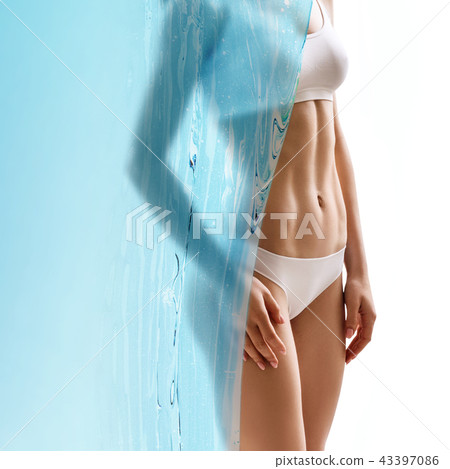 Muscular young woman covered by blue water canvas. 43397086