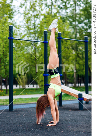 Young sporty woman stands on hand in the park. Young sporty woman stands on hand in the park. 43397278