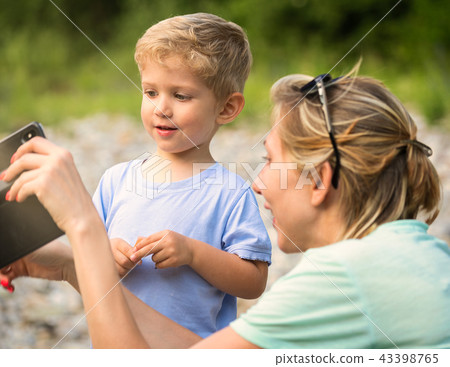 mother and baby are looking at the cell phone mother and baby are looking at the cell phone 43398765