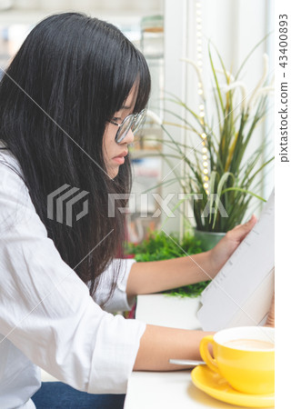 Asian teenager reading book beside window 43400893