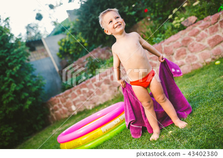 Summer vacation theme. A small 3 year old Caucasian boy playing in the backyard of a house on the 43402380