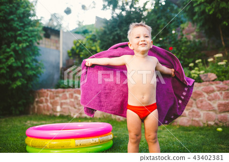 Summer vacation theme. A small 3 year old Caucasian boy playing in the backyard of a house on the 43402381