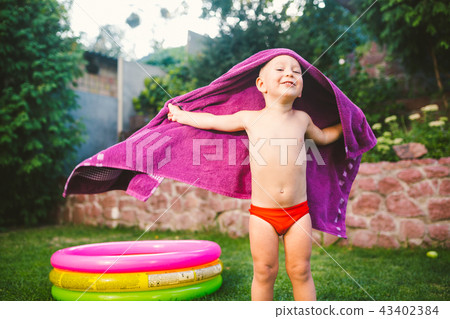 Summer vacation theme. A small 3 year old Caucasian boy playing in the backyard of a house on the 43402384