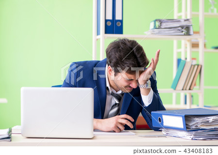 Businessman unhappy with excessive work sitting in the office  43408183