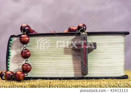 Bible and the crucifix beads on a golden table.  43413113