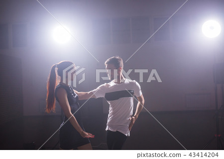 Skillful dancers performing in the dark room under the concert light and smoke. Sensual couple Skillful dancers performing in the dark room under the concert light and smoke. Sensual couple 43414204