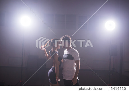 Skillful dancers performing in the dark room under the concert light and smoke. Sensual couple Skillful dancers performing in the dark room under the concert light and smoke. Sensual couple 43414210