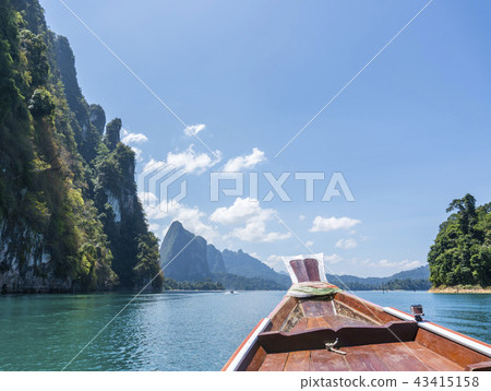 Wooden Thai traditional long-tail boat on a lake with mountains and rain forest in the background 43415158