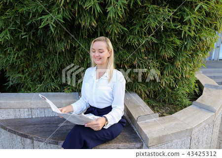 Lady reading newspaper outdoors in with close up face. Lady reading newspaper outdoors in with close up face. 43425312