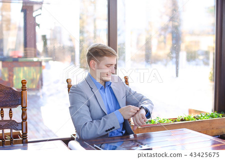 Businessman using smart watch at cafe with roll project, tablet Businessman using smart watch at cafe with roll project, tablet 43425675