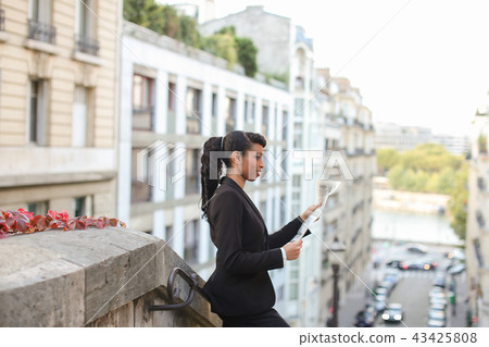 Half Nigerian reporter looking at cam with newspaper on balcony. 43425808