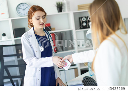 A beautiful young girl in a white robe is standing near a computer desk in the office and 43427269