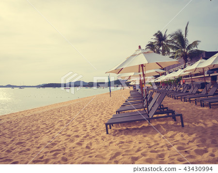 Umbrella and chair on the tropical beach sea and ocean at sunrise time Umbrella and chair on the tropical beach sea and ocean at sunrise time 43430994