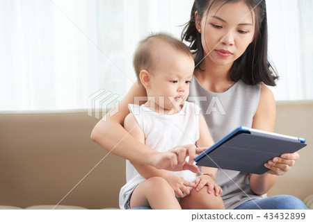 Mother showing tablet to daughter Mother showing tablet to daughter 43432899