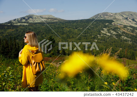 Hipster young girl in yellow raincoat with backpack on peak of mountain. Tourist traveler on Hipster young girl in yellow raincoat with backpack on peak of mountain. Tourist traveler on 43437242