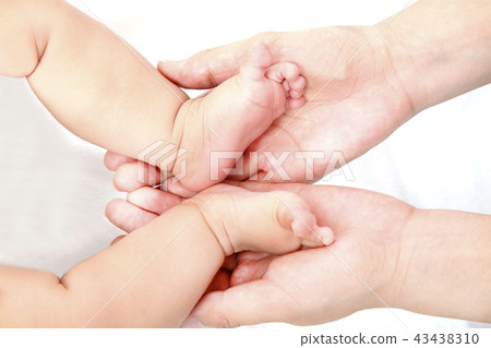 Mother's big hands up of mother wrapping little baby's feet. Image of motherhood, affection, happiness, childcare, health 43438310