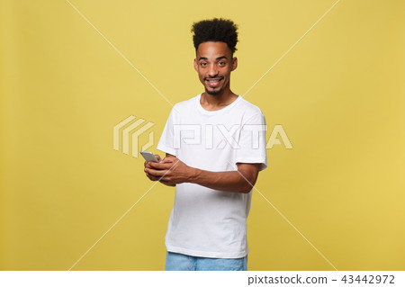 Happy african american man with smiling and using mobile phone. Isolated on yellow background. Happy african american man with smiling and using mobile phone. Isolated on yellow background. 43442972