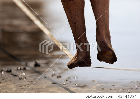 Man legs walk along a tight line in the beach 43444354