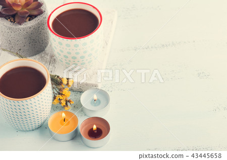 Two mugs of hot cocoa, succulent and lit candles 43445658