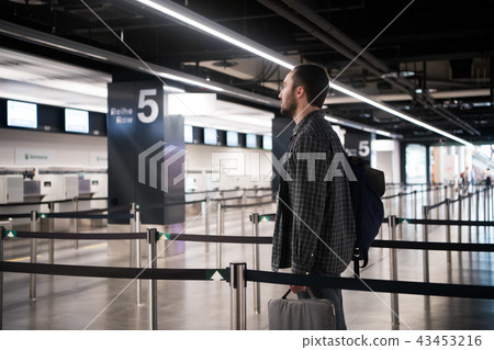 Young man with his luggage and backpack using smartphone while waiting for airline flight in the Young man with his luggage and backpack using smartphone while waiting for airline flight in the 43453216
