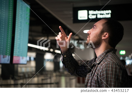 Man In Front Of Arrivals And Departures Board At The Airport. Travel concept Man In Front Of Arrivals And Departures Board At The Airport. Travel concept 43453217