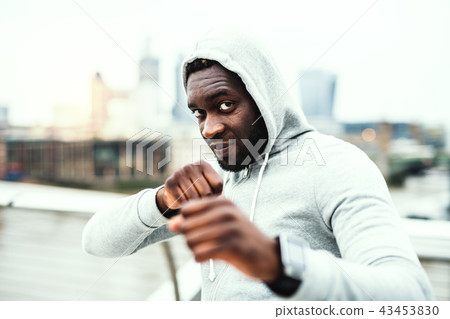 Young active black sportsman in boxing position in a city, wearing hoodie. Young active black sportsman in boxing position in a city, wearing hoodie. 43453830