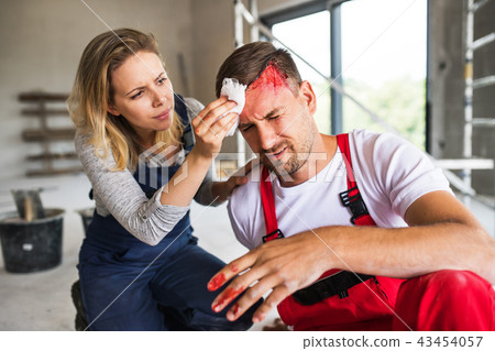A woman helping man worker after an accident at the construction site. 43454057