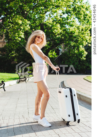 Girl traveler with a white suitcase Girl traveler with a white suitcase 43454646