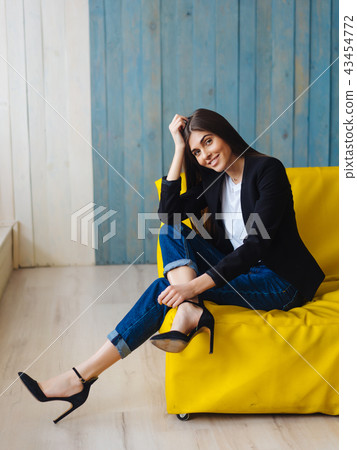 Young woman sitting on yellow sofa 43454772