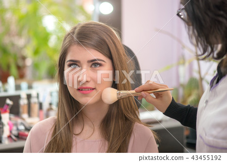 Makeup artist applying makeup to model in salon. Makeup artist applying makeup to model in salon. 43455192