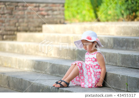 girl wearing white hat  sitting on stairs 43455317