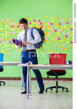 Man in the office with many conflicting priorities preparing go Man in the office with many conflicting priorities preparing go 43456008